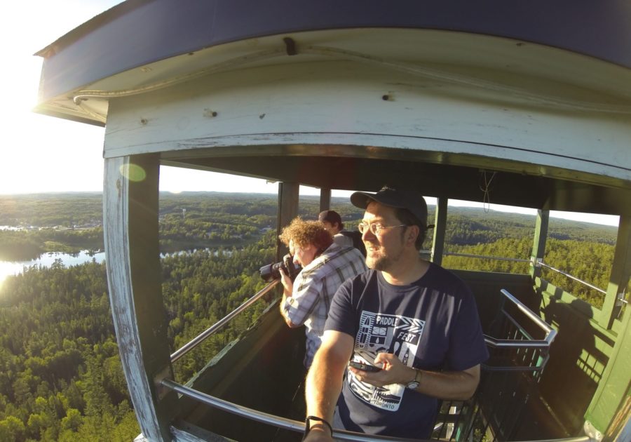 Three people look out from a tower high above the trees