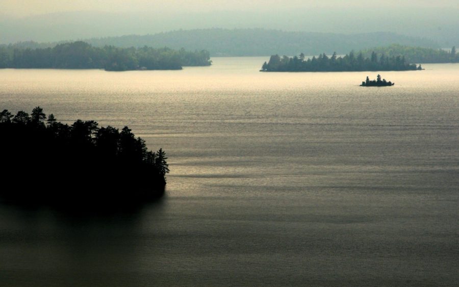 Lake with misty covered forest and grey blue sky overhead