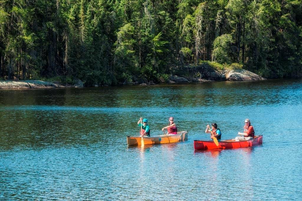 One red and one orange canoe, side by side in a blue lake