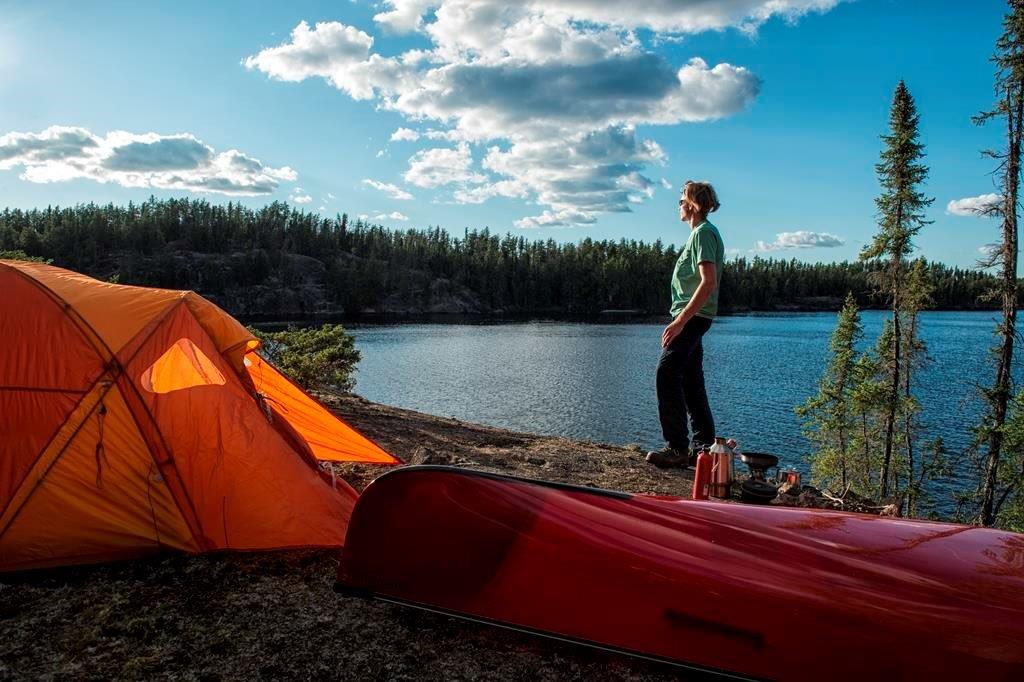 A person admiring the view of the lake and forest from their campsite