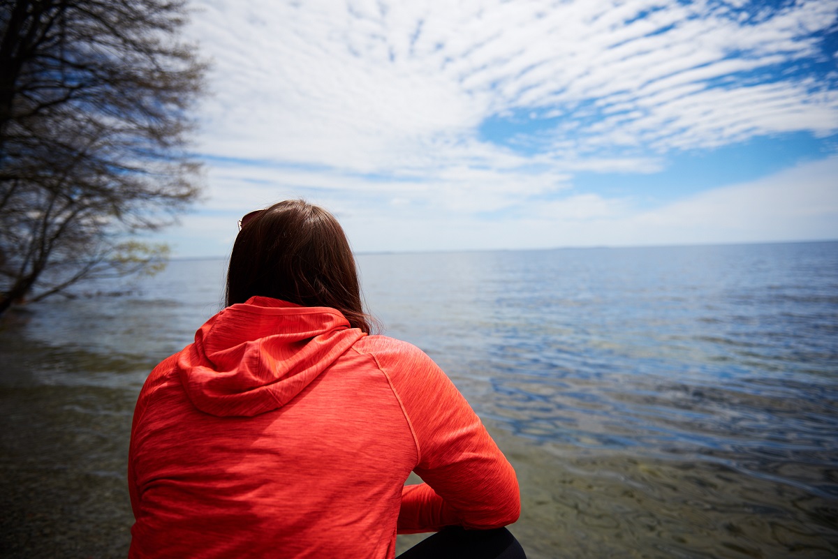 Person in red shirt looking out at the lake - shot from behind