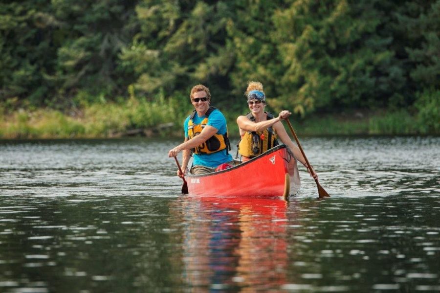 Two people paddling toward camera in a red canoe