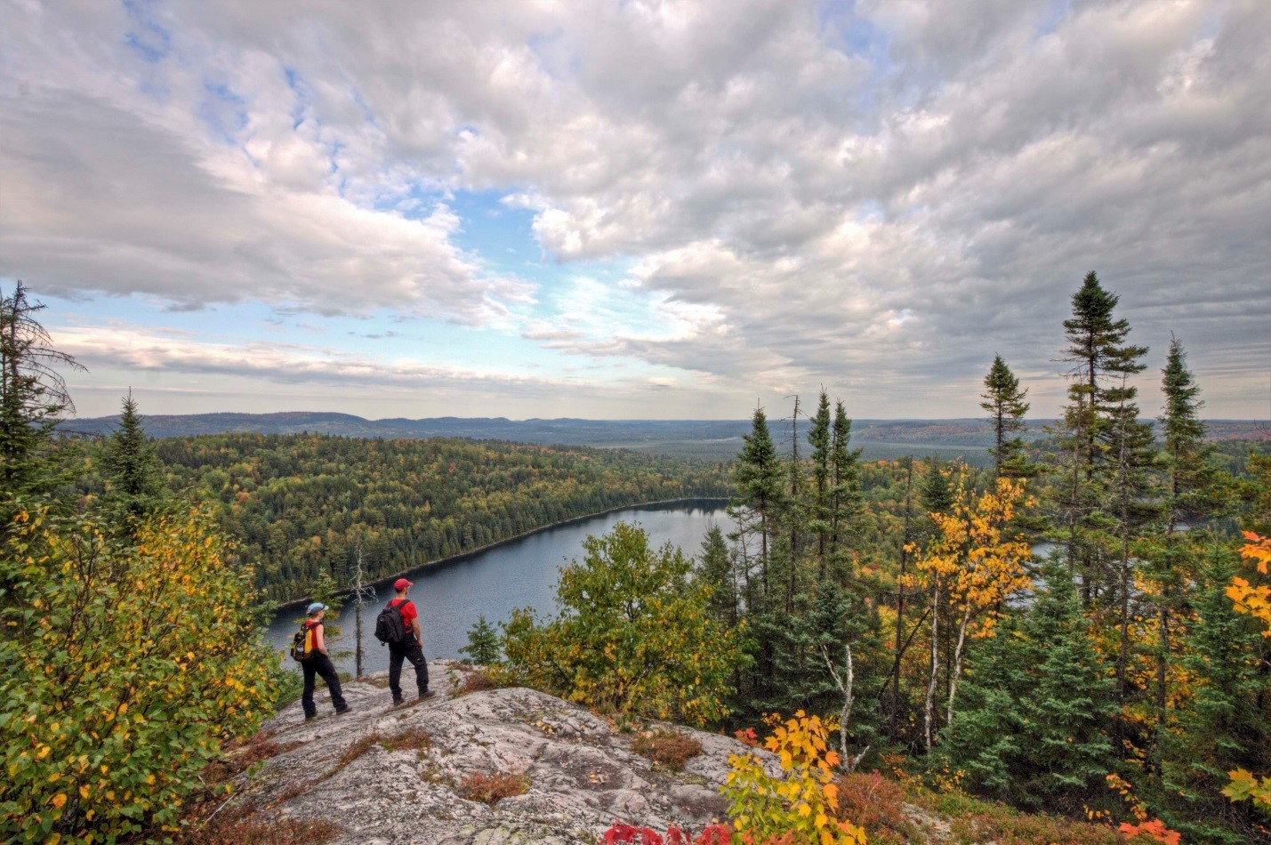 two hikers on lookout over lake and forest