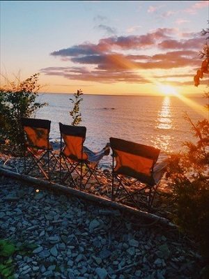 Three folding chairs on the beach at sunset