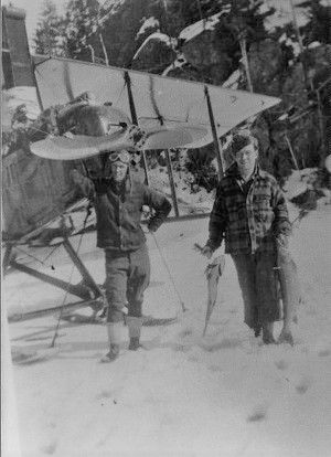 Black and white photo, two men standing in front of a bush plane