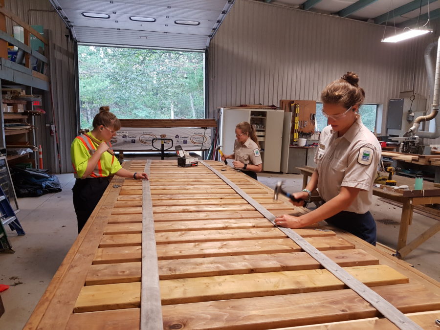 three employees hammering nails into boardwalk