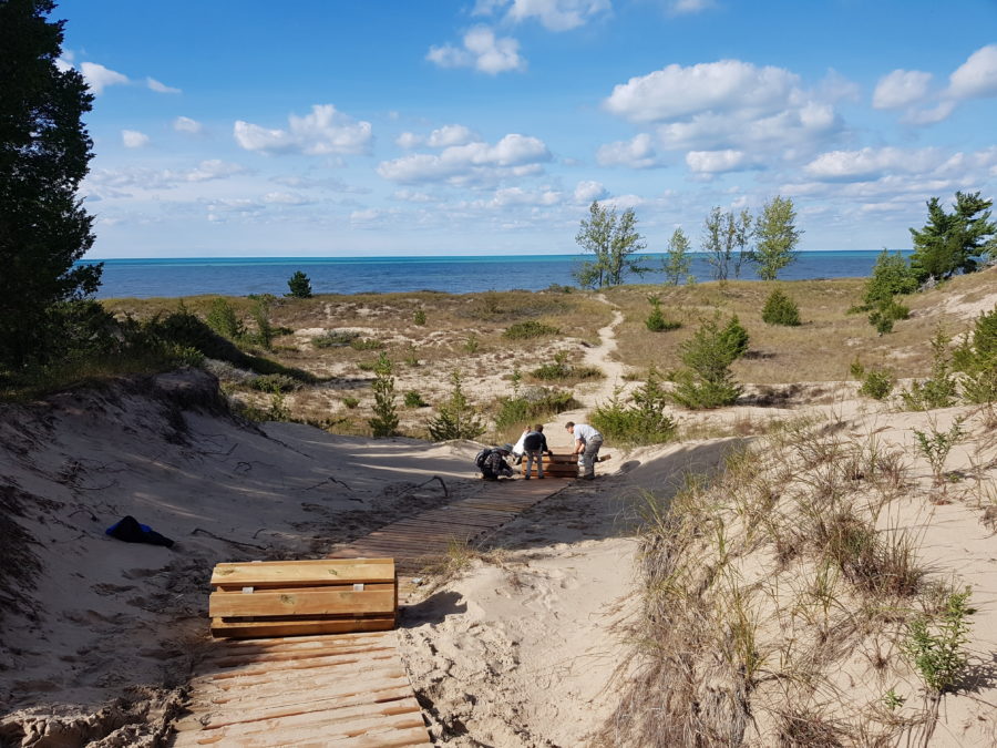 rolling out wooden boardwalk on dune