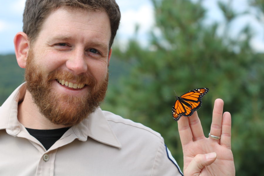 Park staff holding a monarch butterfly while doing the Vulcan salute.