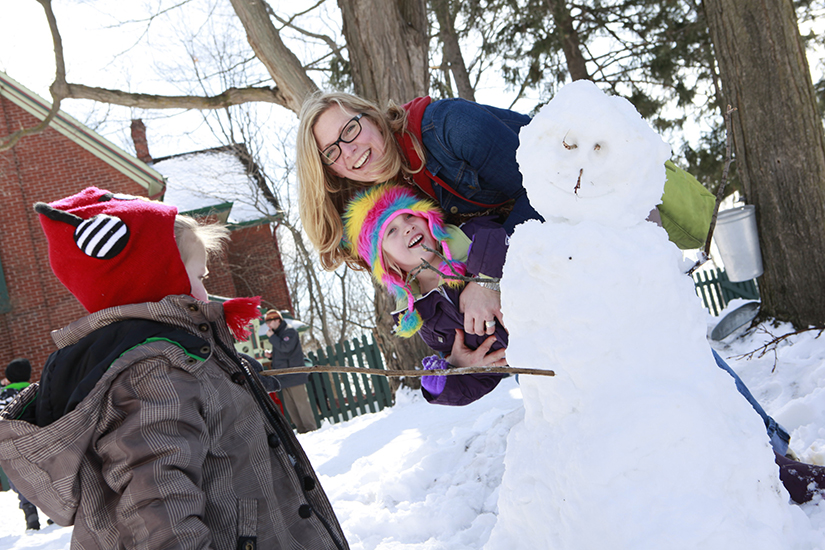 mom and kids building snowman