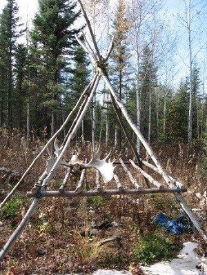 sticks tied together in triangle with grill made of wood