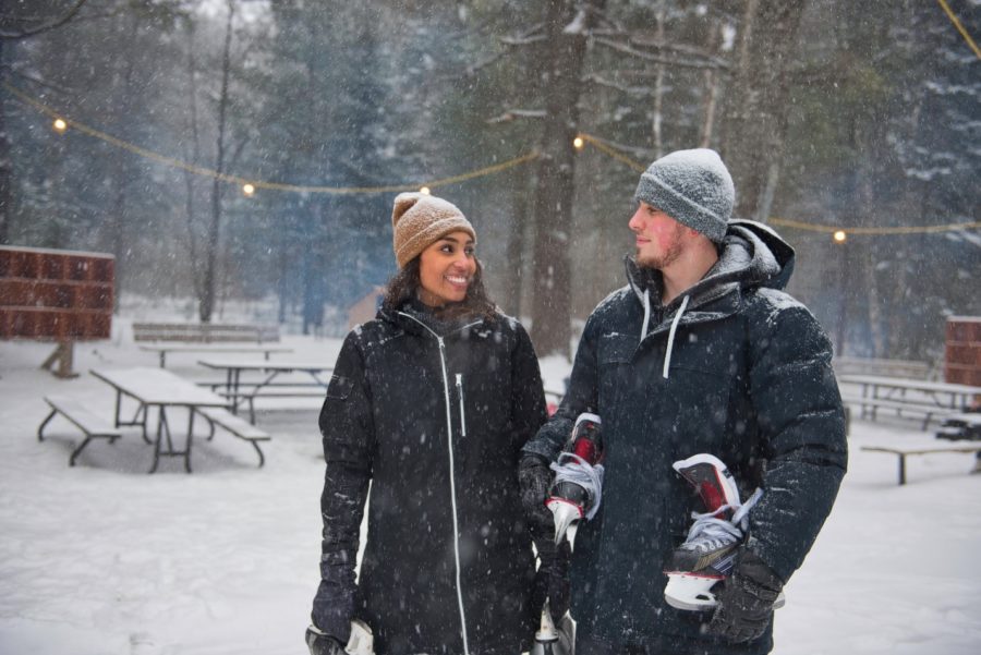 couple holding skates outdoors in snow