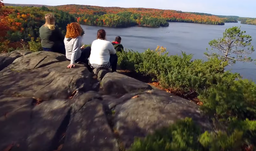 people sitting on cliff overlooking lake