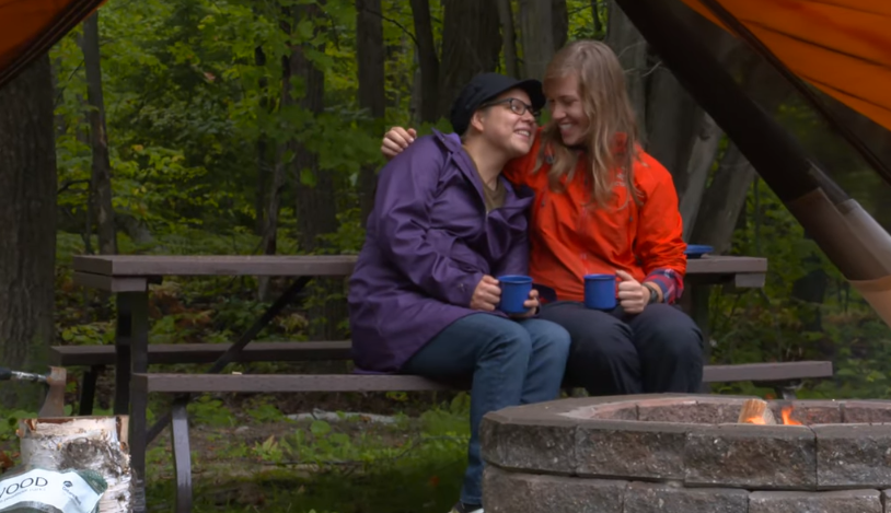 two women sitting by campfire