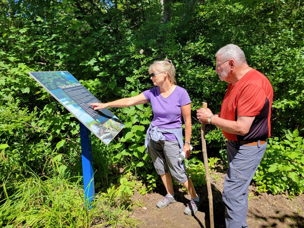 two hikers looking at park sign