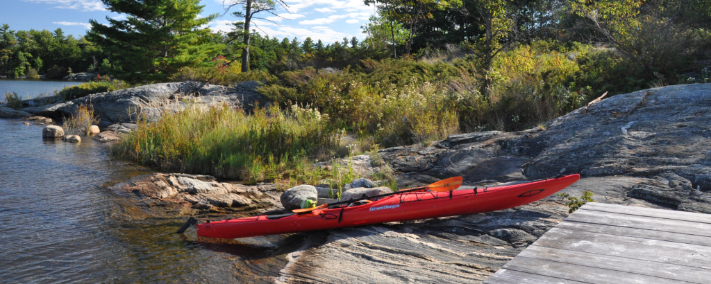 A red kayak on a rocky shore