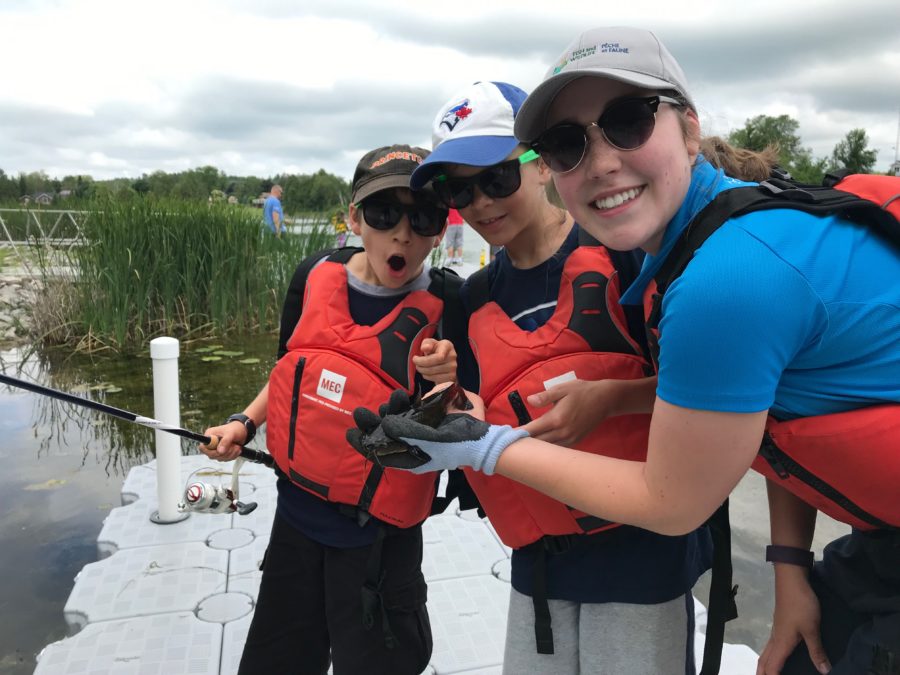 Participants of a Learn to Fish session check out the fish they just caught with Emily's Learn to Fish leader.