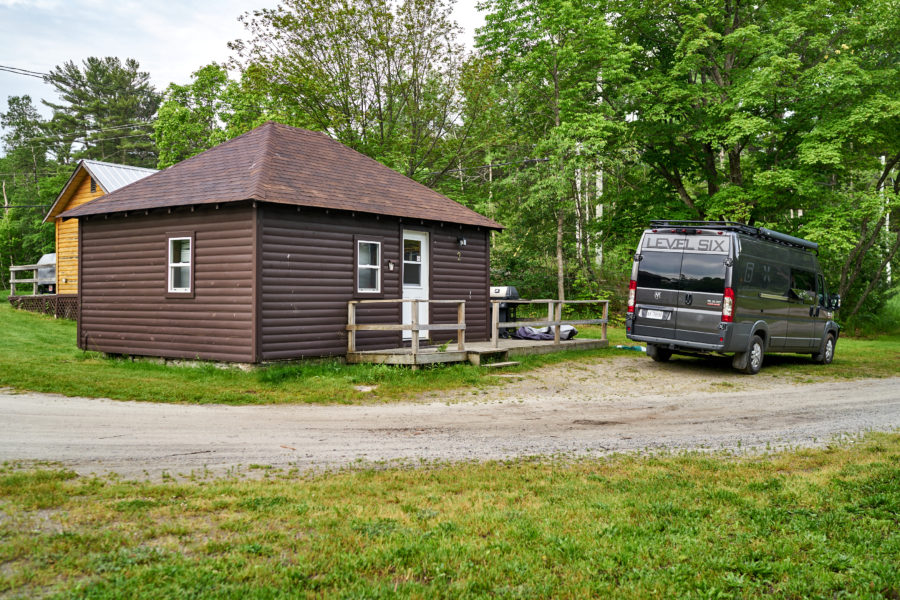 View of the outside of the cabin. Square brown building with a small porch at the front.