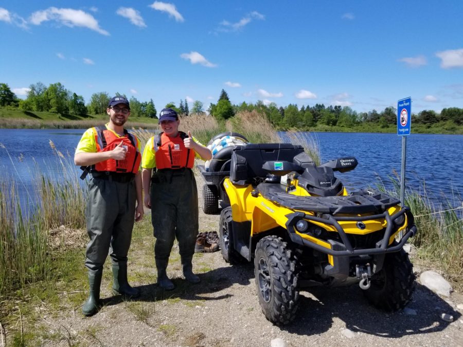 two rangers standing beside ATV