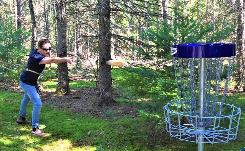 A visitor trying their hand at disc golf at Mikisew.