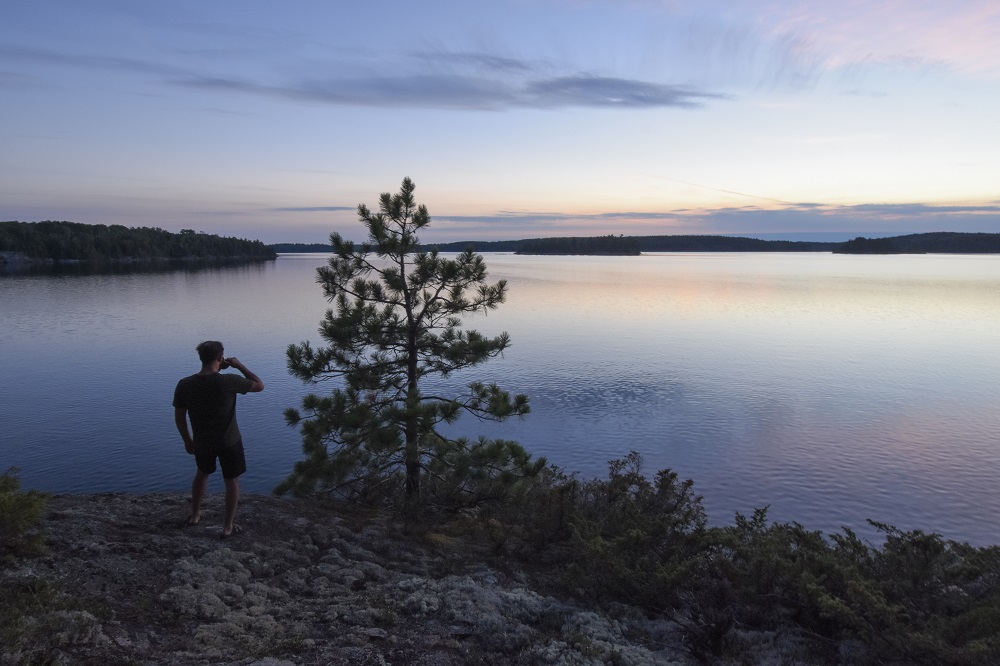 person looking out at lake at sunset