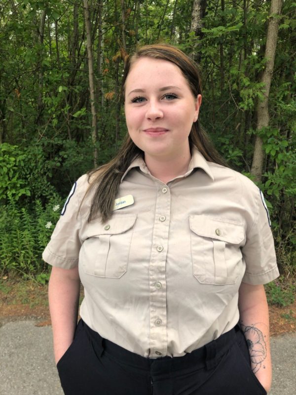 staff in uniform in front of forest