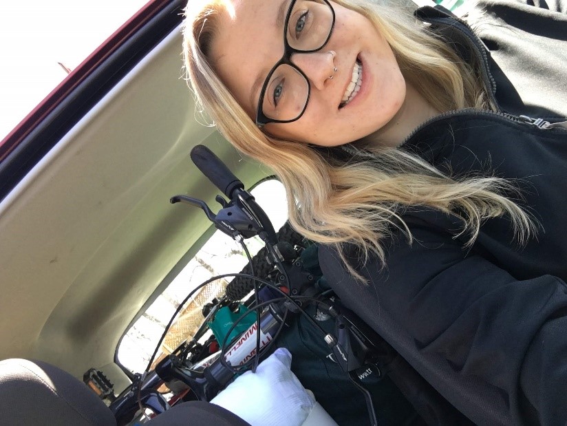 Summer smiling with the view of all the gear she brought with her in the back of the car.