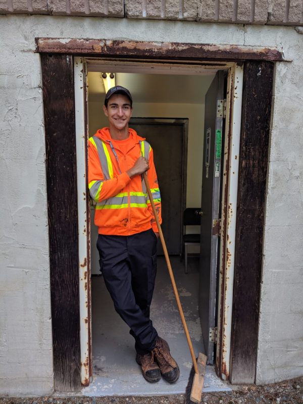 staff holding broom in doorway