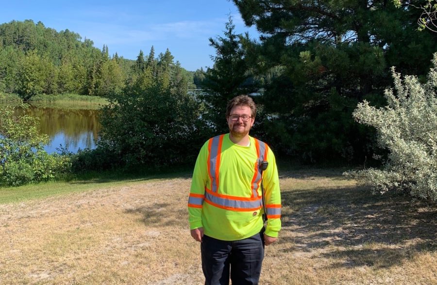 staff in yellow shirt standing in front of lake