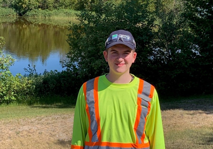 staff in fluorescent shirt in front of pond