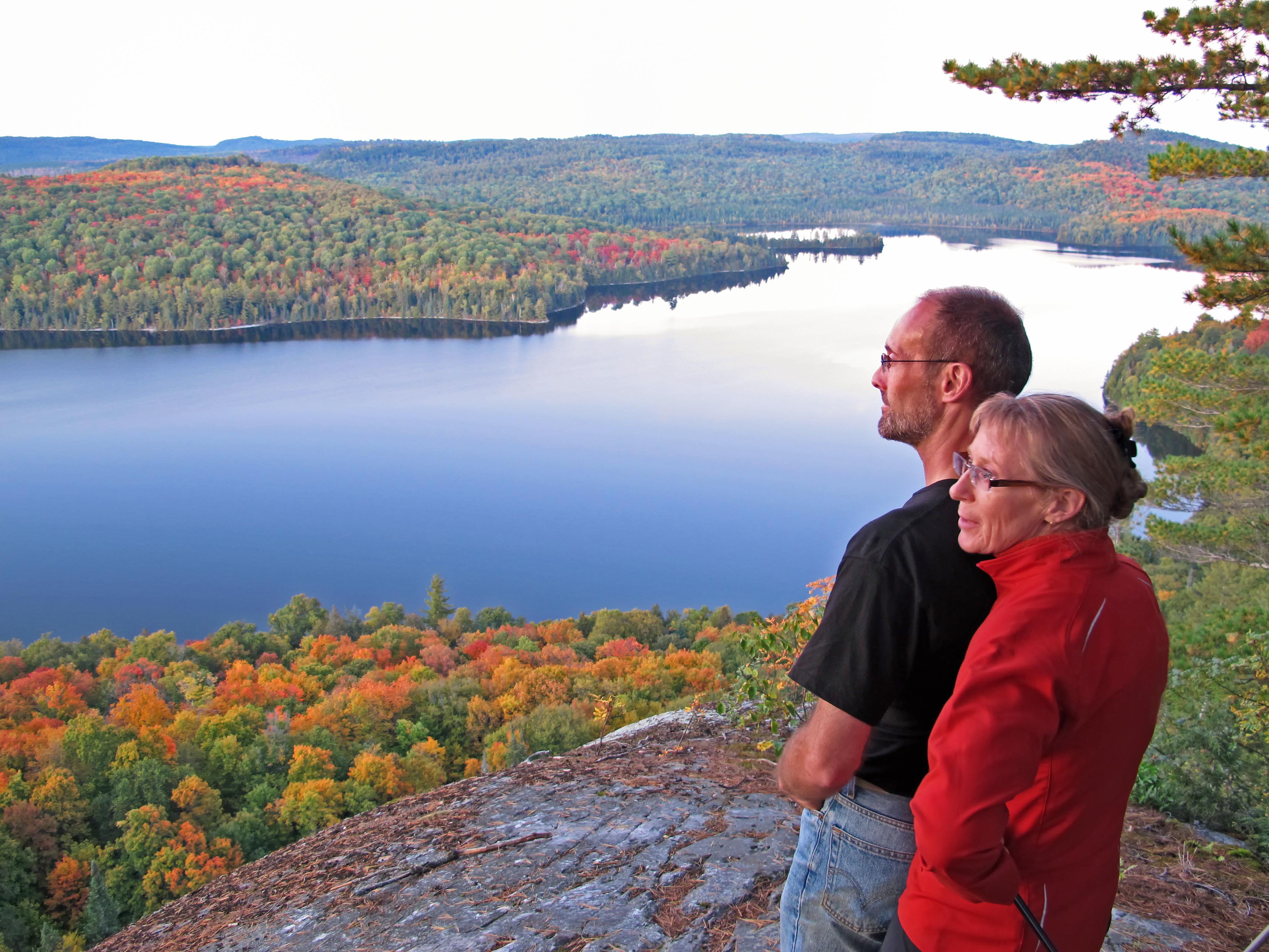 two hikers looking over fall forest and lake