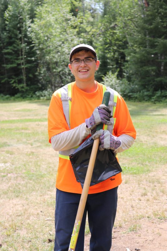 staff in orange holding rake