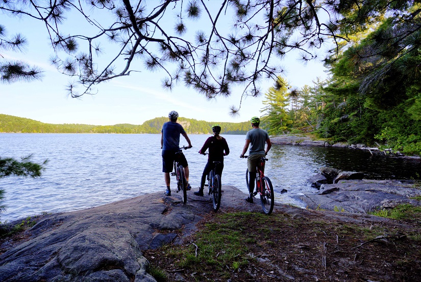 Three bikers look out on shore. 