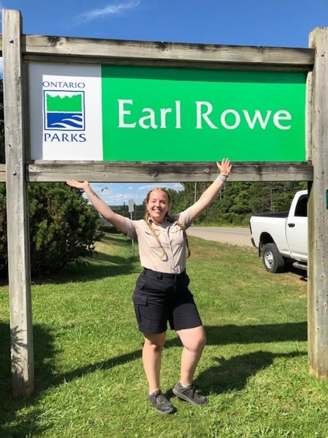 staff standing outside of park sign