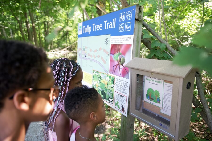 Family looking at sign on Tulip Tree Trail StoryWalk