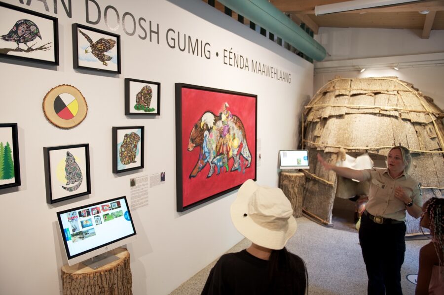 Staff and visitors looking at painting (red background, bear filled with different imagery)