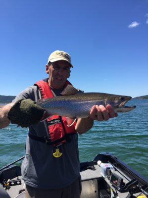 Staff member holding a Coaster standing in the boat.