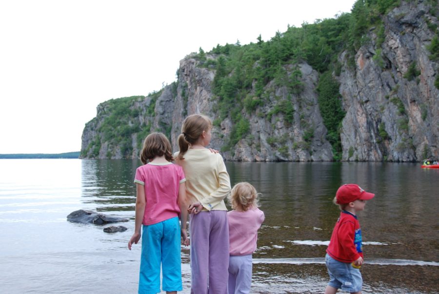 Children standing by the water edge with Mazinaw Rock in the background.