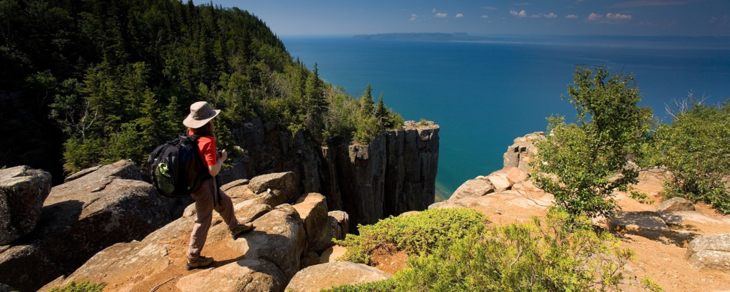 person standing on rocky edge, looking out at lake