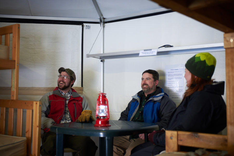 Three men sitting inside a yurt