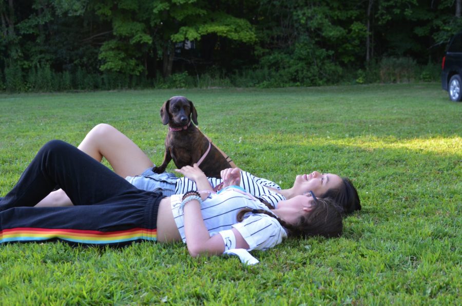 Two girls lying on a blanket with a dog