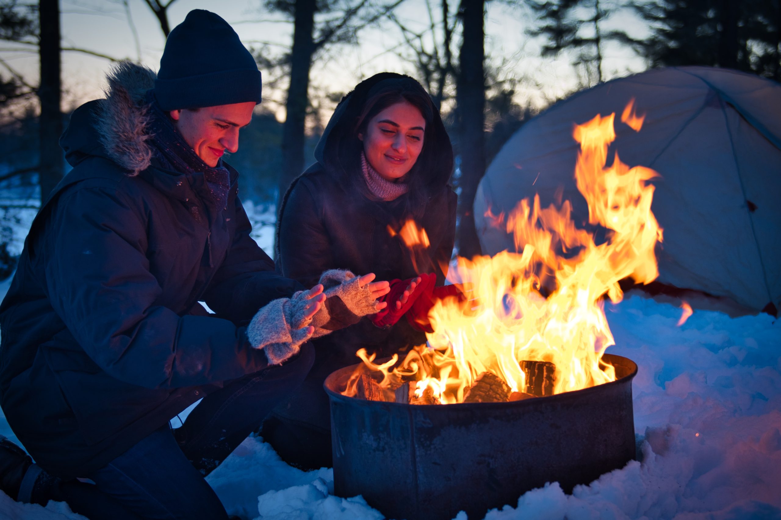 Two winter campers around campfire at Frontenac Provincial Park