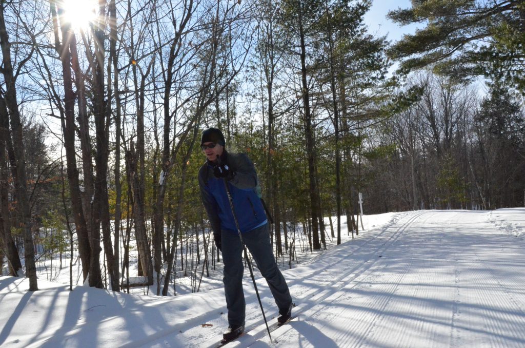 A person skiing on a groomed ski trail in a forest