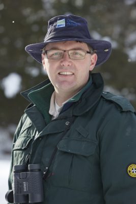 Alistair in green uniform coat and Ontario Parks hat