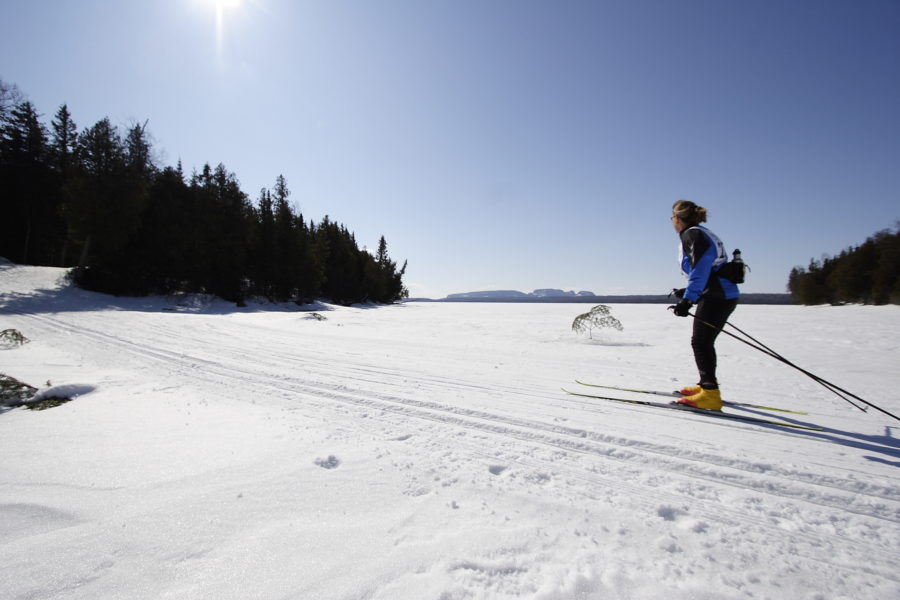 Someone skiing across an open part of the lake