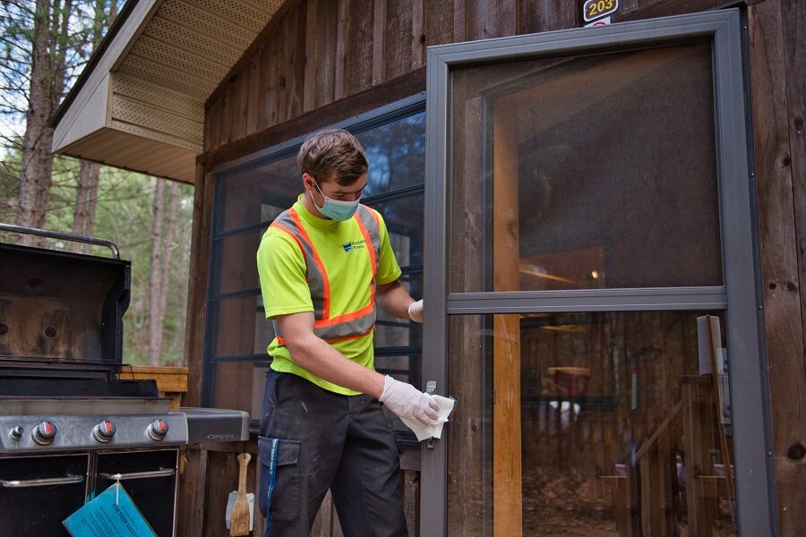 Staff disinfecting door at cabin, Arrowhead.