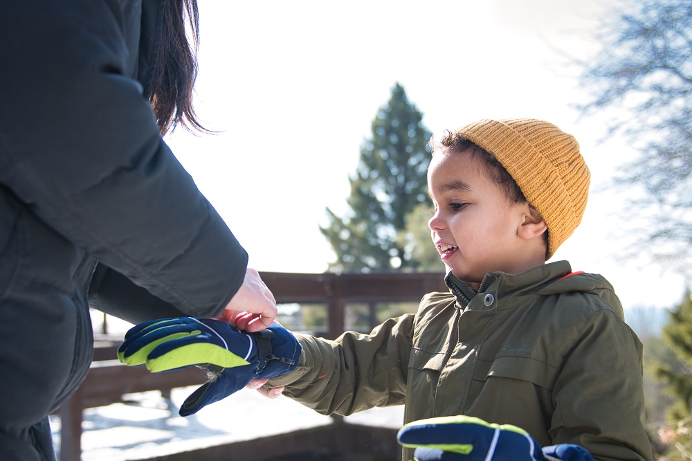 mother putting gloves on child