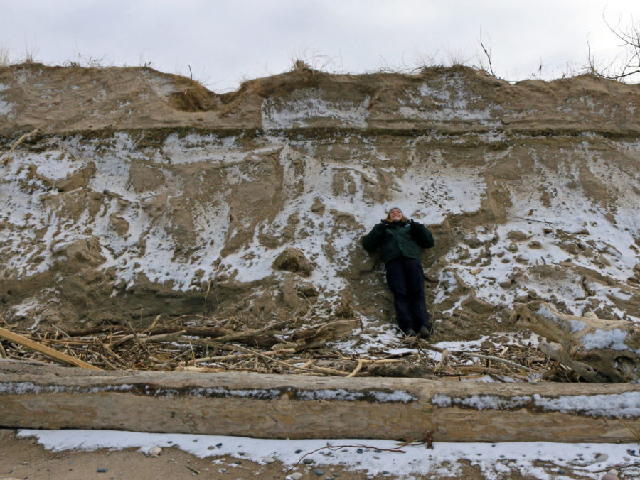 A staff member shows the scale of the erosion.