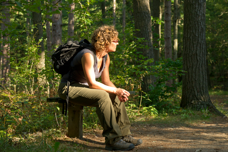 hiker sitting on bench beside trail