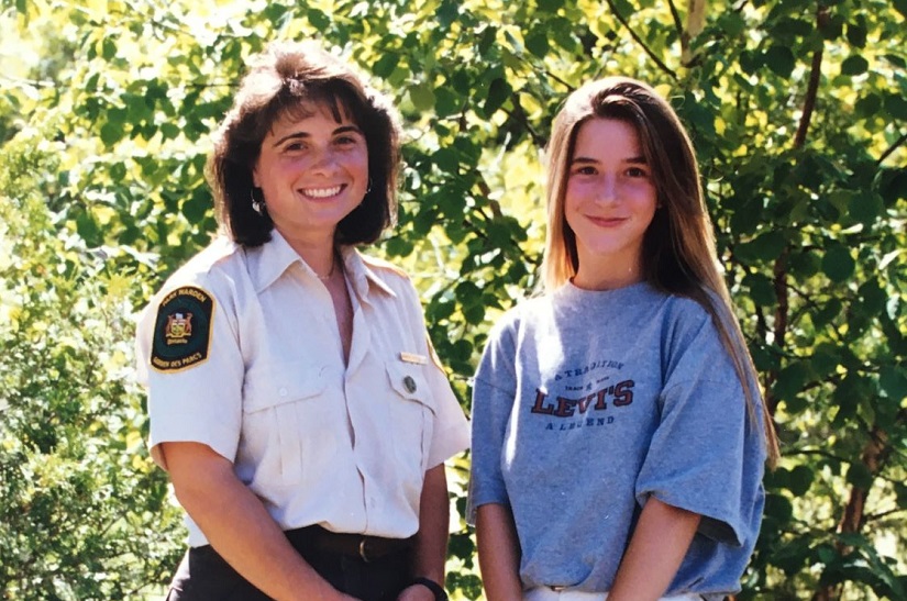 Staff member and woman stand in front of tree