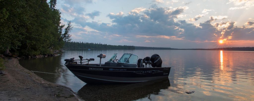 motorboat docked on lake's shore at sunset
